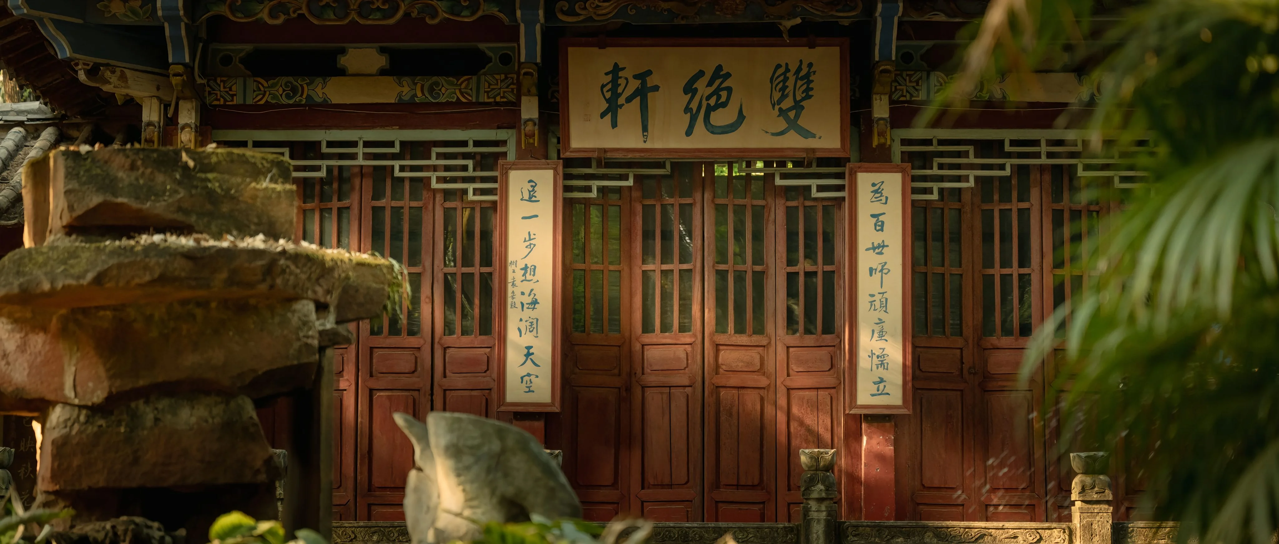 Ornate wooden doors of the Shuang Jue Xuan (Double Excellence Pavilion) in Kunming, adorned with vertical calligraphy couplets and traditional Chinese architectural motifs.