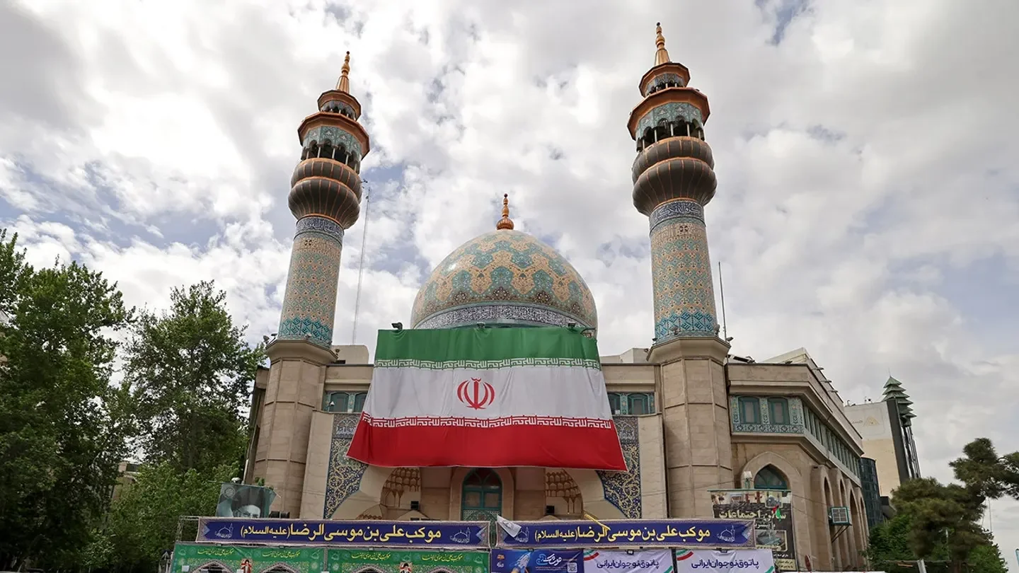 Motorists ride past the Imam Sadiq mosque with a giant Iranian flag installed on its front at the Palestine Square in Tehran on April 19, 2026. (Atta Kenare/AFP via Getty Images)
