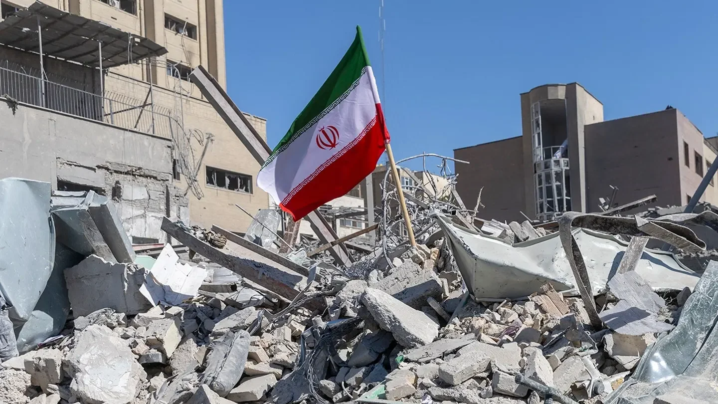 An Iranian flag is planted in the rubble of a police station, damaged in airstrikes on March 3, 2026, in Tehran, Iran. (Majid Saeedi/Getty Images)