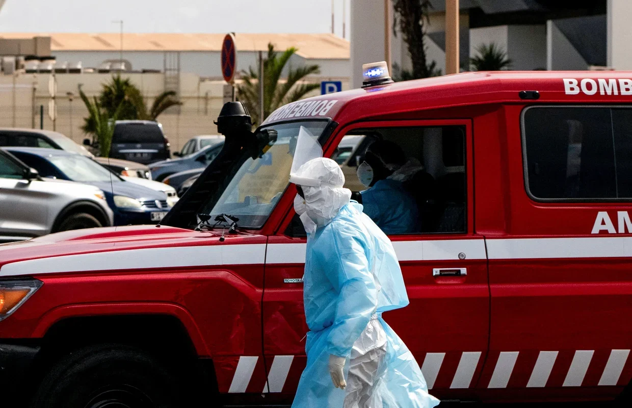 A person in protective clothing walks next to an ambulance during an evacuation of suspected hantavirus patients, following an outbreak on the cruise ship MV Hondius, in Praia, Cape Verde, May 6, 2026. Danilson Sequeira / REUTERS